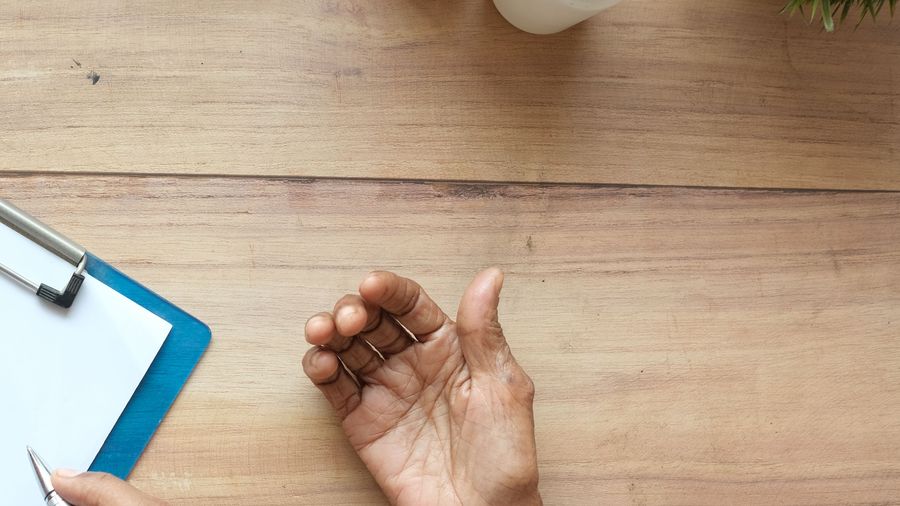 An older person's hands resting on a table during a home visit.